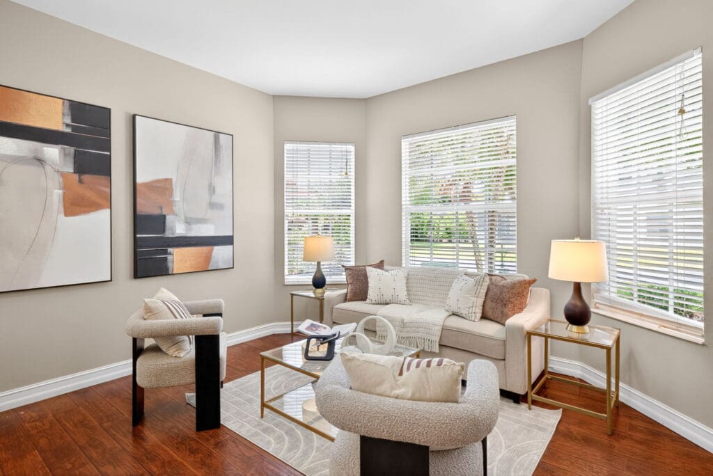 Strategic house staging by stageandamaze demonstrating clean, simple interior design in a sunlit living space with neutral furniture and abstract art.