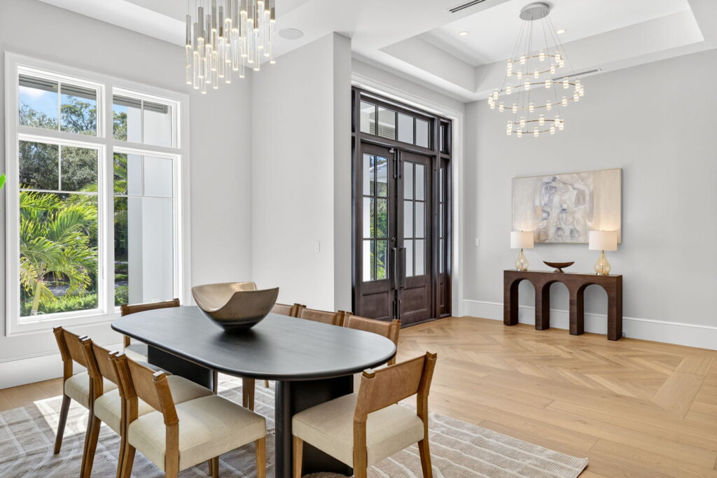 Alt text: Professionally staged luxury dining room at Bow Line in The Moorings neighborhood, featuring modern furnishings, statement lighting, intentional styling, and bright open spaces.